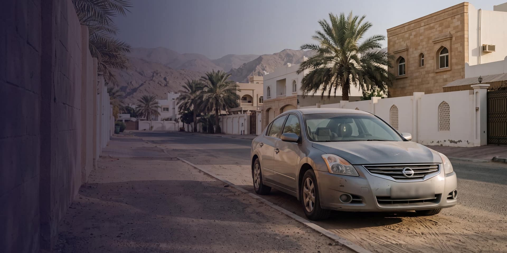 A quiet street in Muscat with an ordinary used car parked at the kerb